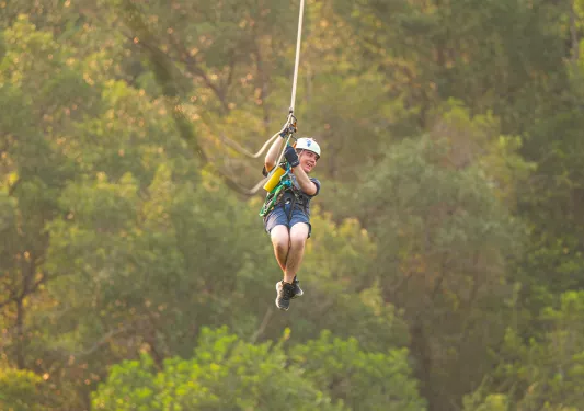 Woman ziplining in the middle of a forest