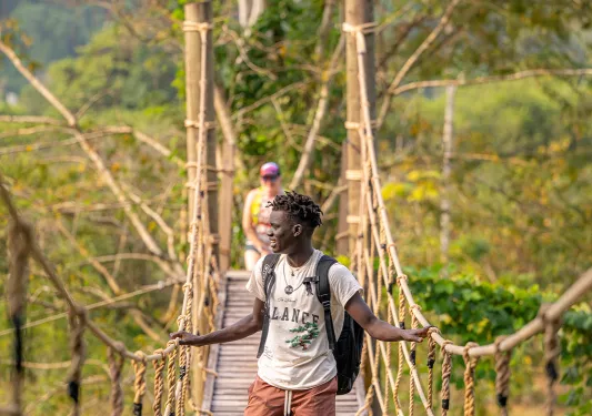 Man walking across a rope and wooden bridge