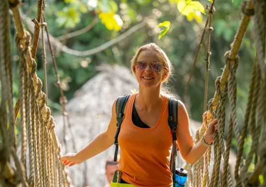 Female walking along a rope bridge in the forest