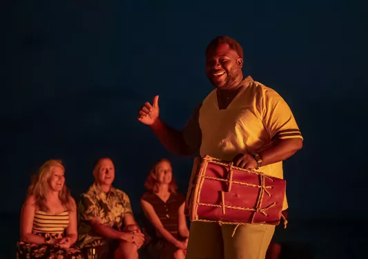 Man holding bongo with a group of people behind him