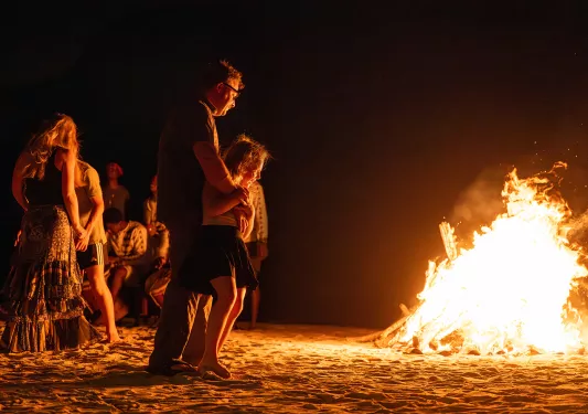 Father and daughter looking at a campfire