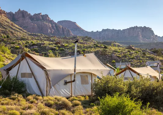 Large, luxury hut tents in the middle of a valley with canyons in the background