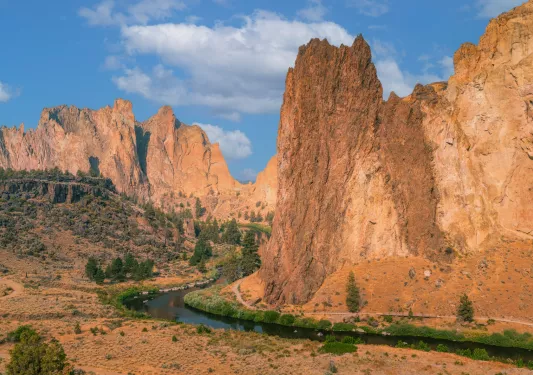Large, orange canyons with a river on the ground level