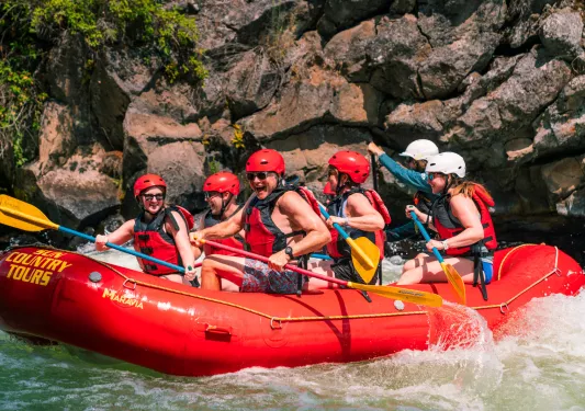 Group of people on a red raft, paddling through a river