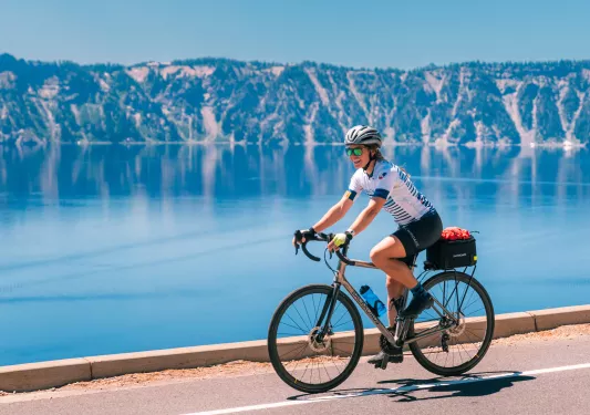 Woman smiling while riding a bike next to a large lake