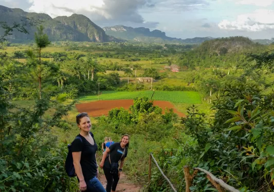 Group of women hiking up a dirt trail, with large valley in the distance