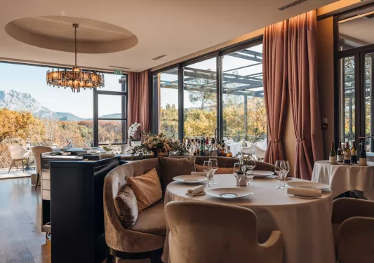 Indoor dining area with large, tan curtains and an open area looking out towards mountains