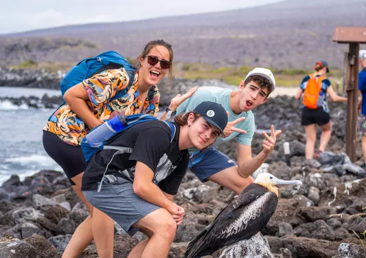 Three teenagers pose with a bird