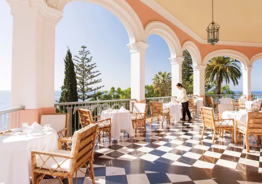 Outdoor patio with dining tables and a waitress prepping the tables