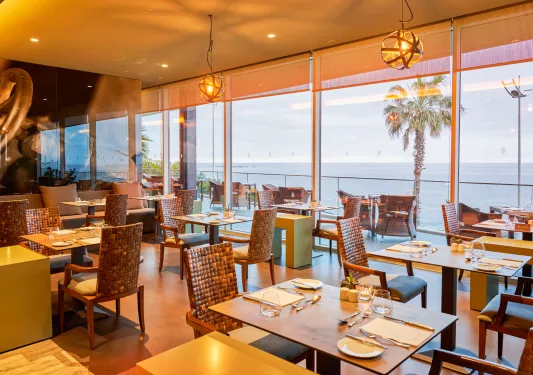 Indoor dining area with a balcony overlooking the ocean