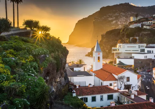 Sunset hitting a small town, filled with white and red buildings on cliffs
