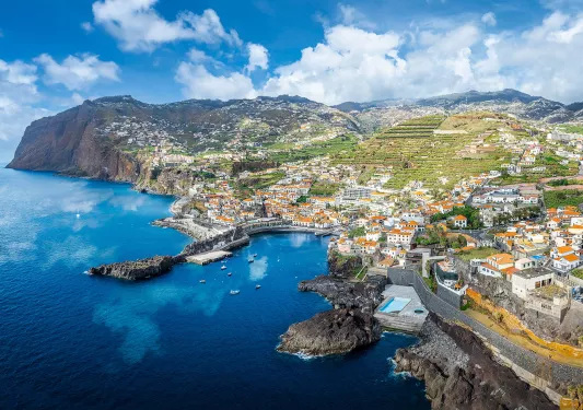 Sky view of a oceanside town with large mountains in the background