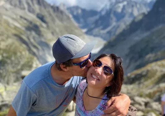 Man kissing woman on the cheek on top of a cliff