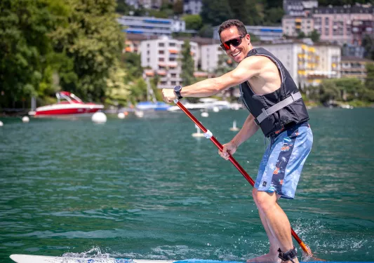 Man smiling while paddle boarding in a lake