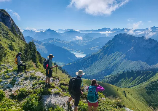 Group of people on top of a cliff looking down at grassy hills