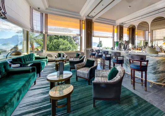 Bar and lounge with large open windows and a bartender in the background