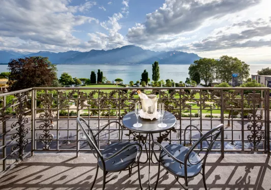 Balcony with two metal chairs and a table with a bottle of alcohol on it
