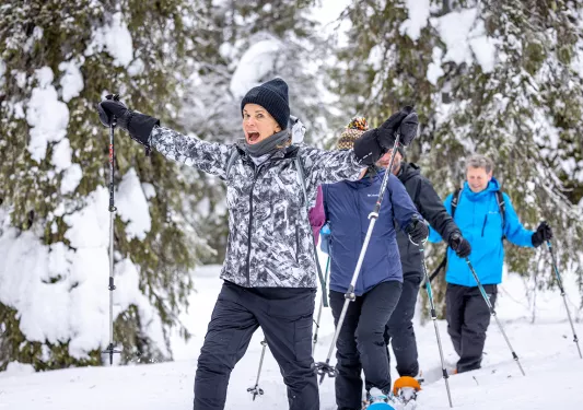 A group of people in snowshoes walk a snowed over path