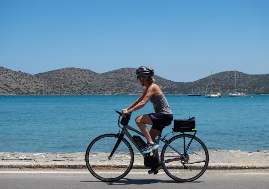 Woman on an e-bike along a road next to the ocean