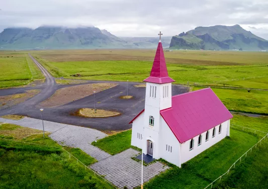 White and red church building in the middle of a grass valley