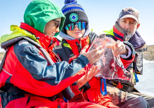 Two boys holding a large, clear block of ice