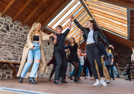 Group of people dancing in a wood and stone lodge