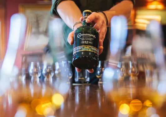 Person holding up a bottle of Irish whiskey at a dining table