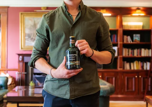 Man smiling while holding a bottle of Irish whiskey