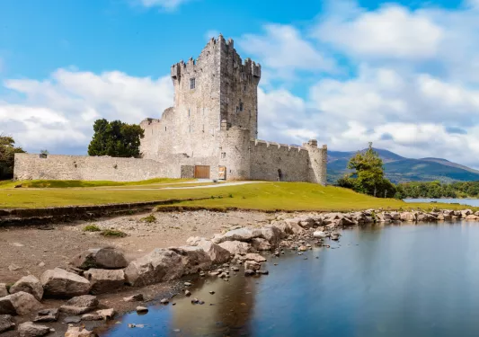 Castle-like building in an open valley, with a small lake in front