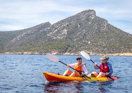 Man and woman rowing in a kayak, in the middle of a large lake