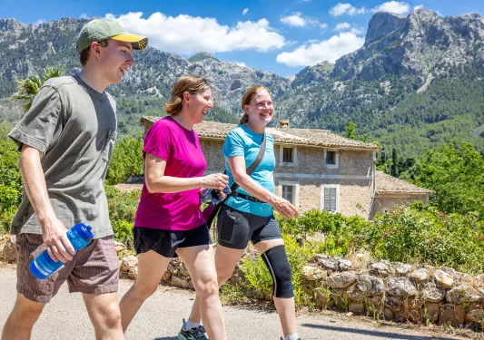 Two women and one man smiling while walking in a small town