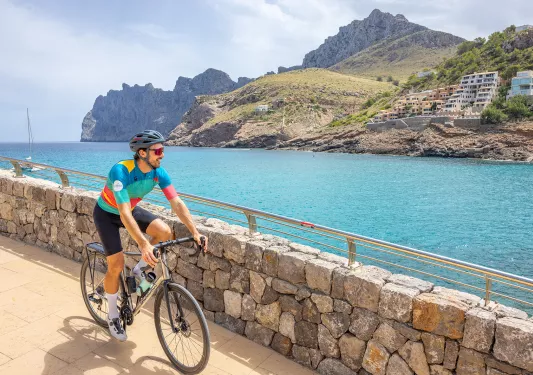 Man biking on a stone path looking out to a lake and a small town