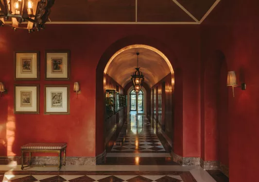 Red hallway with marble floors and pictures on the wall