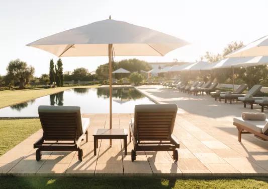 lounge chairs under umbrella by the pool