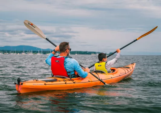 Man and son paddling inside of an orange kayak