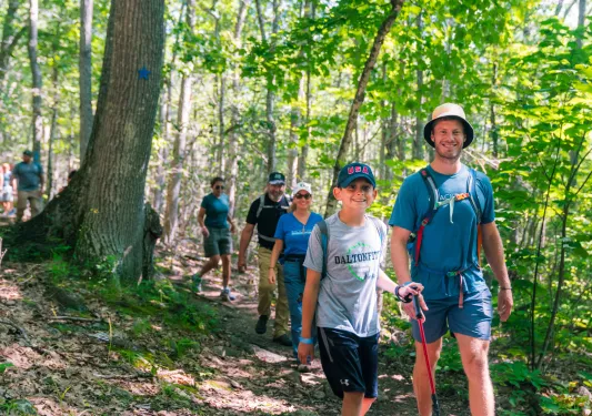 Group of families hiking on a dirt trail in a forest