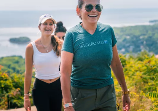 Three women smiling while ascending up a dirt trail