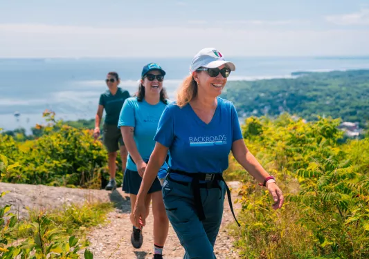 Three women smiling as they are hiking on a dirt trail