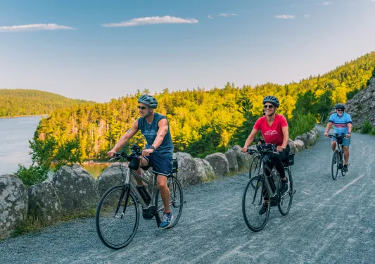Two men and one woman riding bikes on gravel roads