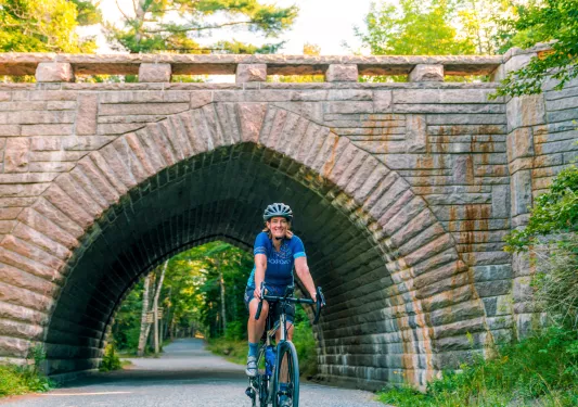 Woman smiling while riding a bike through a brick tunnel