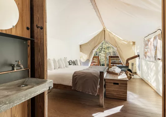 Indoor view of a hite hut, with a stone sink and a white bed
