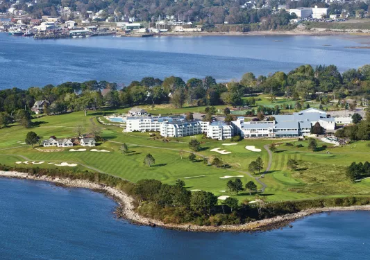Sky view of large white buildings in the middle of a grass field on a peninsula
