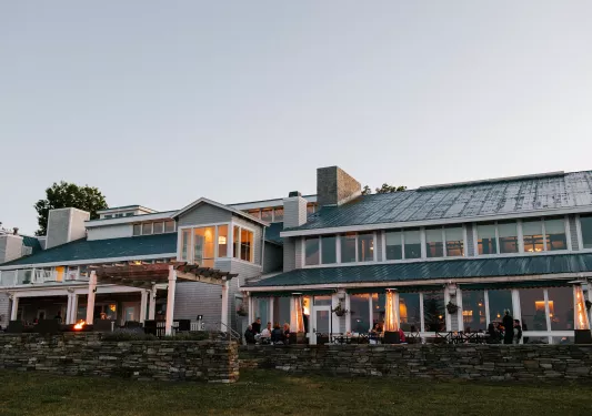 Exterior view of green and white building with an outdoor, stone patio