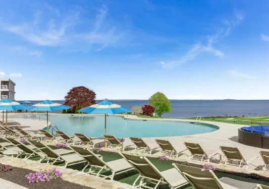 Outdoor pool with blue umbrellas, looking out to the ocean in the distance