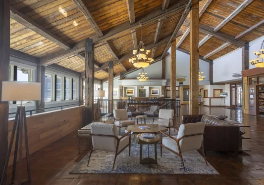 Indoor cabin lobby, with wooden pillars and tan chairs around a coffee table