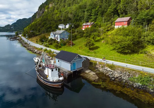 a boat docked by a boathouse on a riverbank