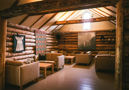 Wooden cabin room with cushioned chairs and paintings on the walls