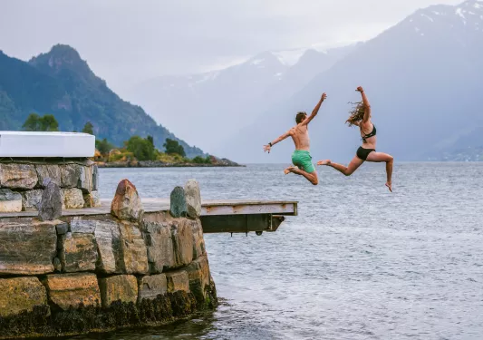 two guest jump off a dock into water