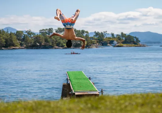 Man backflipping from the ledge into a lake