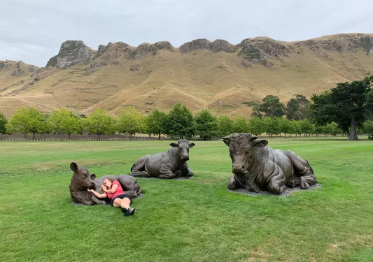Woman laying down with statues of three cows